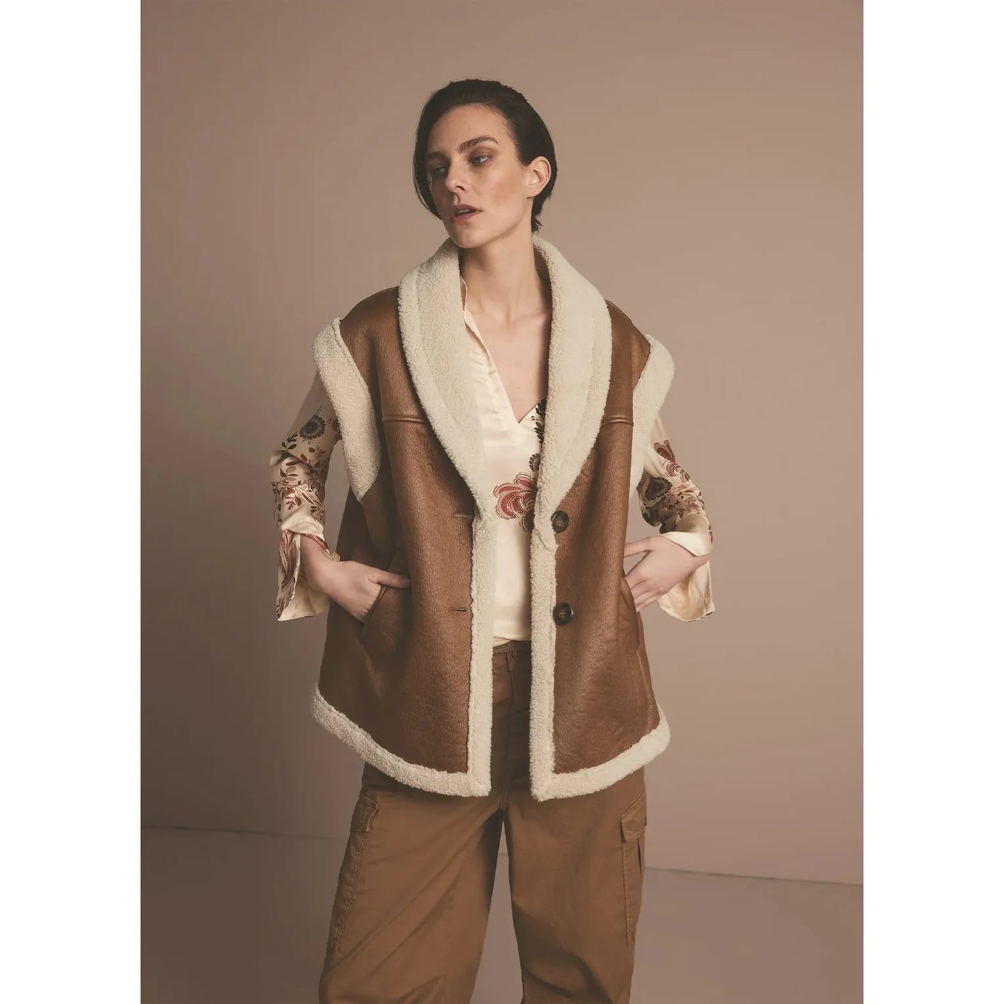 This lammy gilet is sleeveless and has an oversized fit. The gilet’s cuffs are made of teddy fabric. The lapel-style neckline has extra-wide faming with teddy, accentuating the neckline. The lammy jacket has two large buttons and slit pockets in the front.